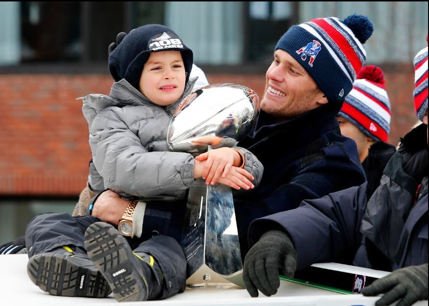 Tom Brady, el estrella de New England Patriots, en el desfile homenaje por la victoria en el Super Bowl XLIX. Su hijo Benjamin Brady abraza el Trofeo Vince Lombardi.