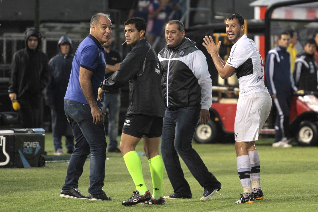 ASUNCION, PARAGUAY - DECEMBER 09: Coach Francisco Arce, coach of Cerro Porteño (C), Blas Cristaldo (L) and Freddy Bareriro of Olimpia, appeal to the fourth referee Enrique Cáceres, during a playoff final match between Cerro Porteño and Olimpia as part of Torneo Apertura 2015 at Defensores del Chaco Stadium on December 09, 2015 in Asuncion, Paraguay. (Photo by Luis Vera/LatinContent/Getty Images)