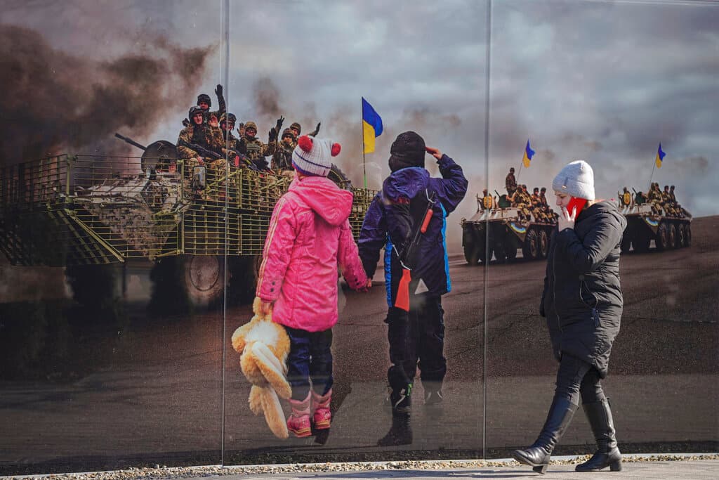 Una mujer pasea frente a un mural fotográfico que recuerda la anterior invasión de Rusia a Ucrania, en 2014. El ataque se este jueves ha hecho caer en picado los
<a href="https://www.univision.com/noticias/dinero/mercados-internacionales-precio-petroleo-wall-street-invasion-rusia-ucrania">mercados internacionales y ha empujado los precios del petróleo por encima de los 100 dólares el barril</a>.