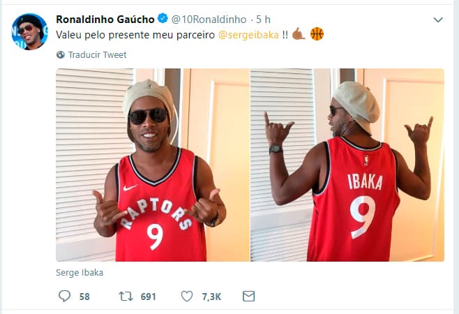 El exfutbolista brasileño Ronaldinho agradece y luce la jersey que le obsequió el jugador congolés naturalizado español Serge Ibaka, de los Toronto Raptors de la NBA.