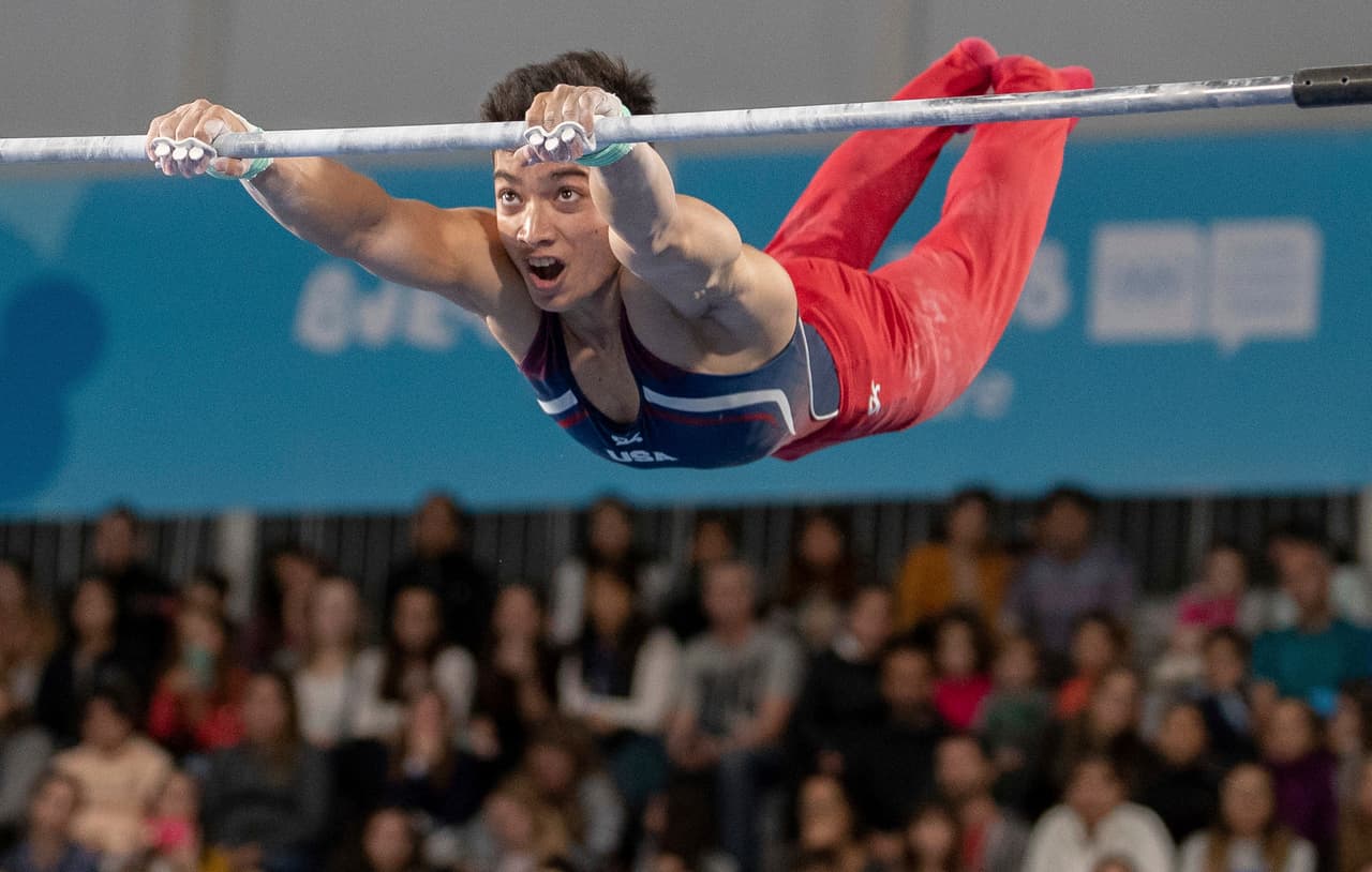 Brandon Briones, de los Estados Unidos y parte del equipo de la legendaria Oksana Chusovitna, compite en la prueba de barra en el evento multi disciplinario de la gimnasia artística.
