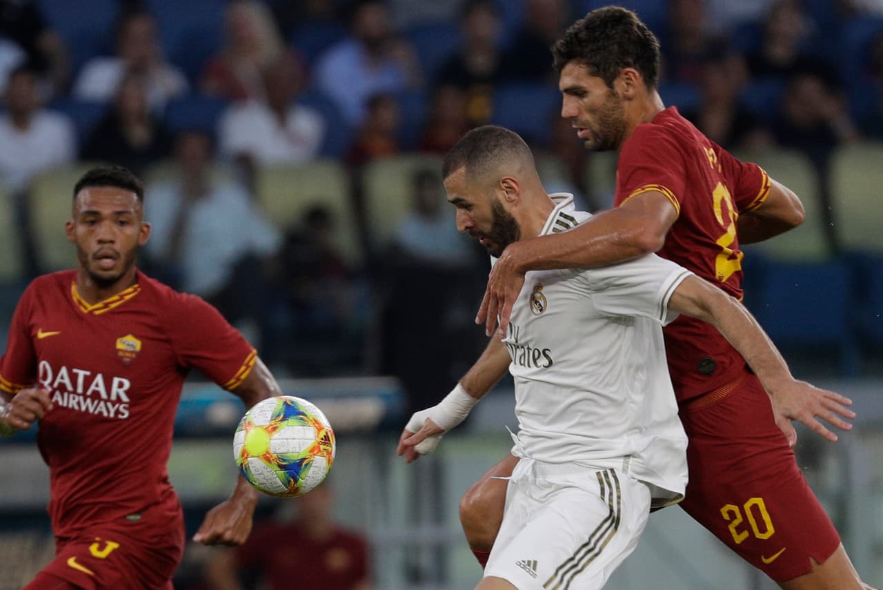 Karim Benzema le mete el cuerpo a Federico Fazio para cubrir el balón.