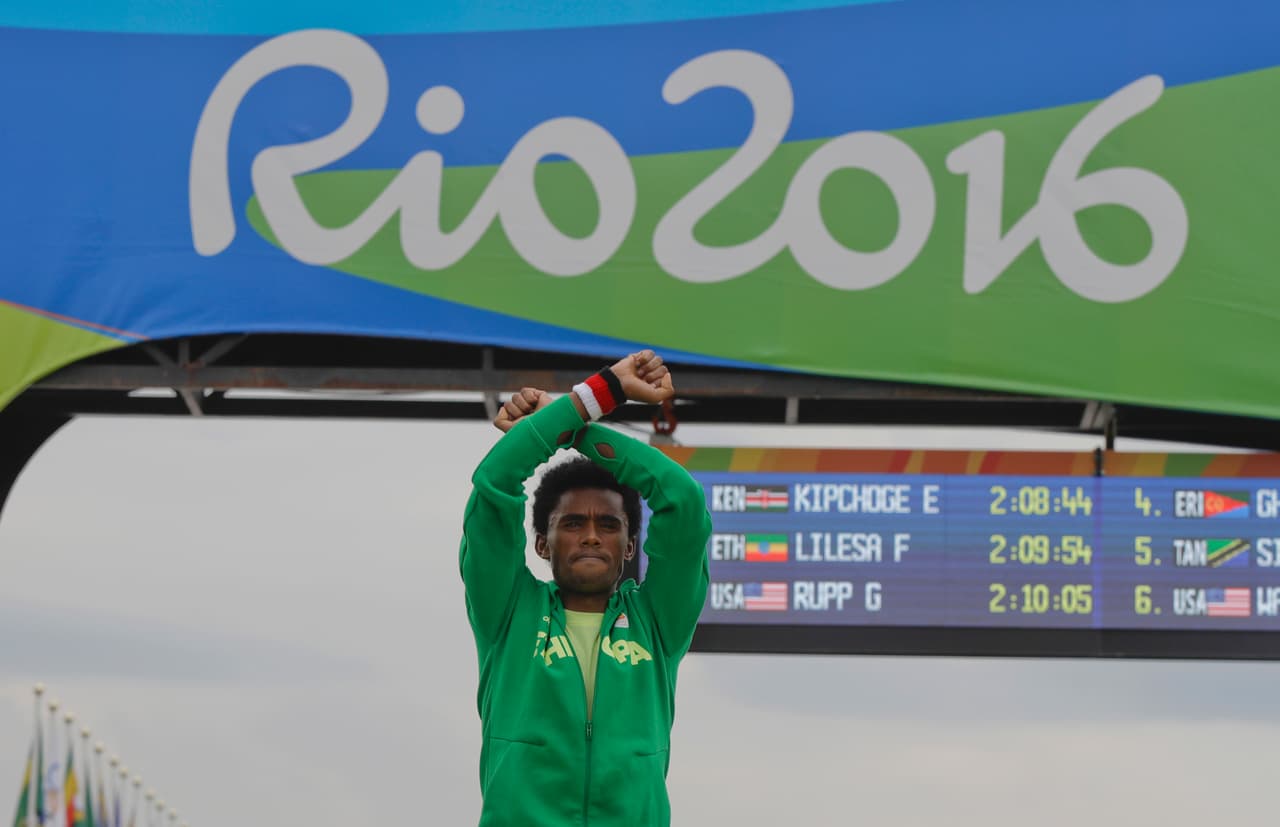 La ganadora de la medalla de plata, la etíope Feyisa Lillesa, cruzó sus brazos mientras celebraba en el podio durante los Juegos Olímpicos de Río 2016. Lilesa estuvo exiliada de su país por opresión mientras ganaba medalla olímpica. Posterior a esto, la Federación Etíope de Atletismo le pidieron regresar a casa y darle una “bienvenida de héroe”.