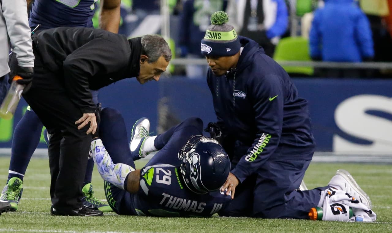 Seattle Seahawks free safety Earl Thomas (29) is examined by team physician Dr. Ed Khalfayan, left, after going down with an injury in the first half of an NFL football game against the Carolina Panthers, Sunday, Dec. 4, 2016, in Seattle. (AP Photo/Ted S. Warren)