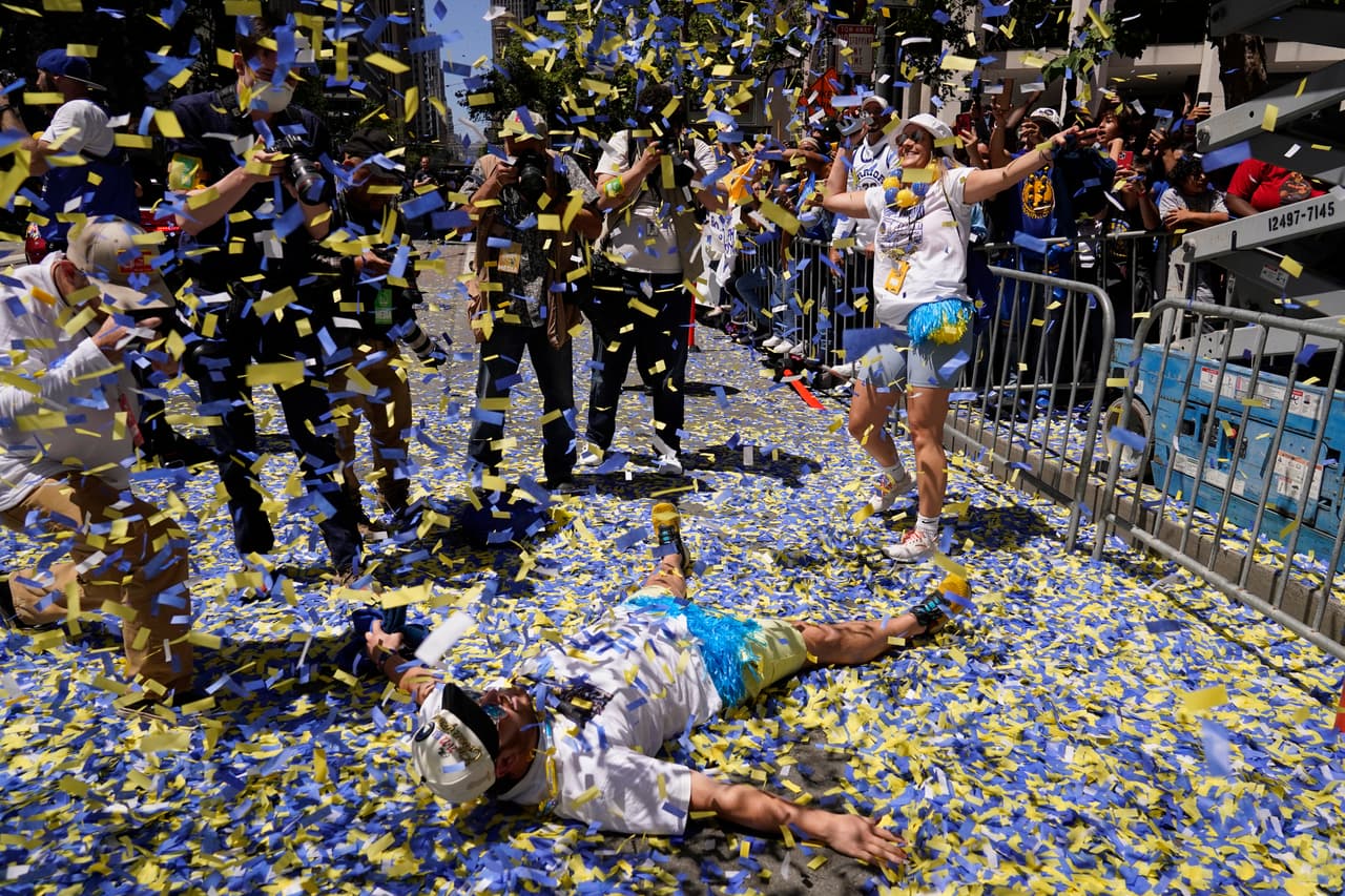 Un hombre se acuesta en Market Street mientras llueve confeti durante el desfile por el campeonato de la NBA de los Golden State Warriors en San Francisco, el lunes 20 de junio de 2022. (Foto AP/Eric Risberg)
