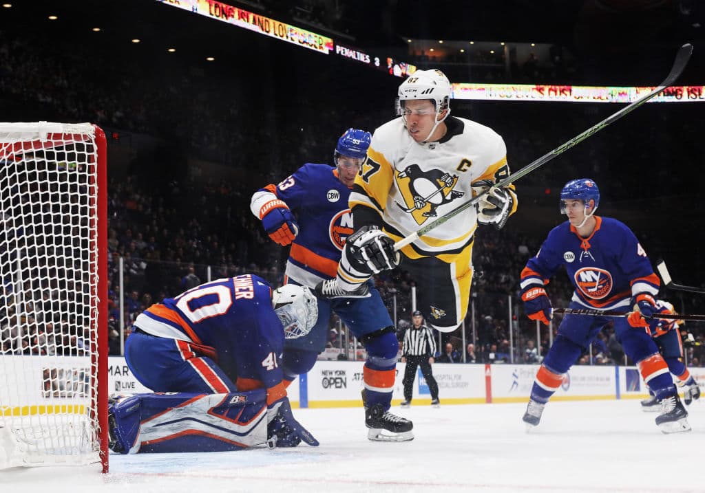 EL capitán de los Pittsburgh Penguins Sydney Crosby (87) hace un salto para no arrollar al porteros de los New York Islanders Robin Lehner (40) y cometer un castigo.