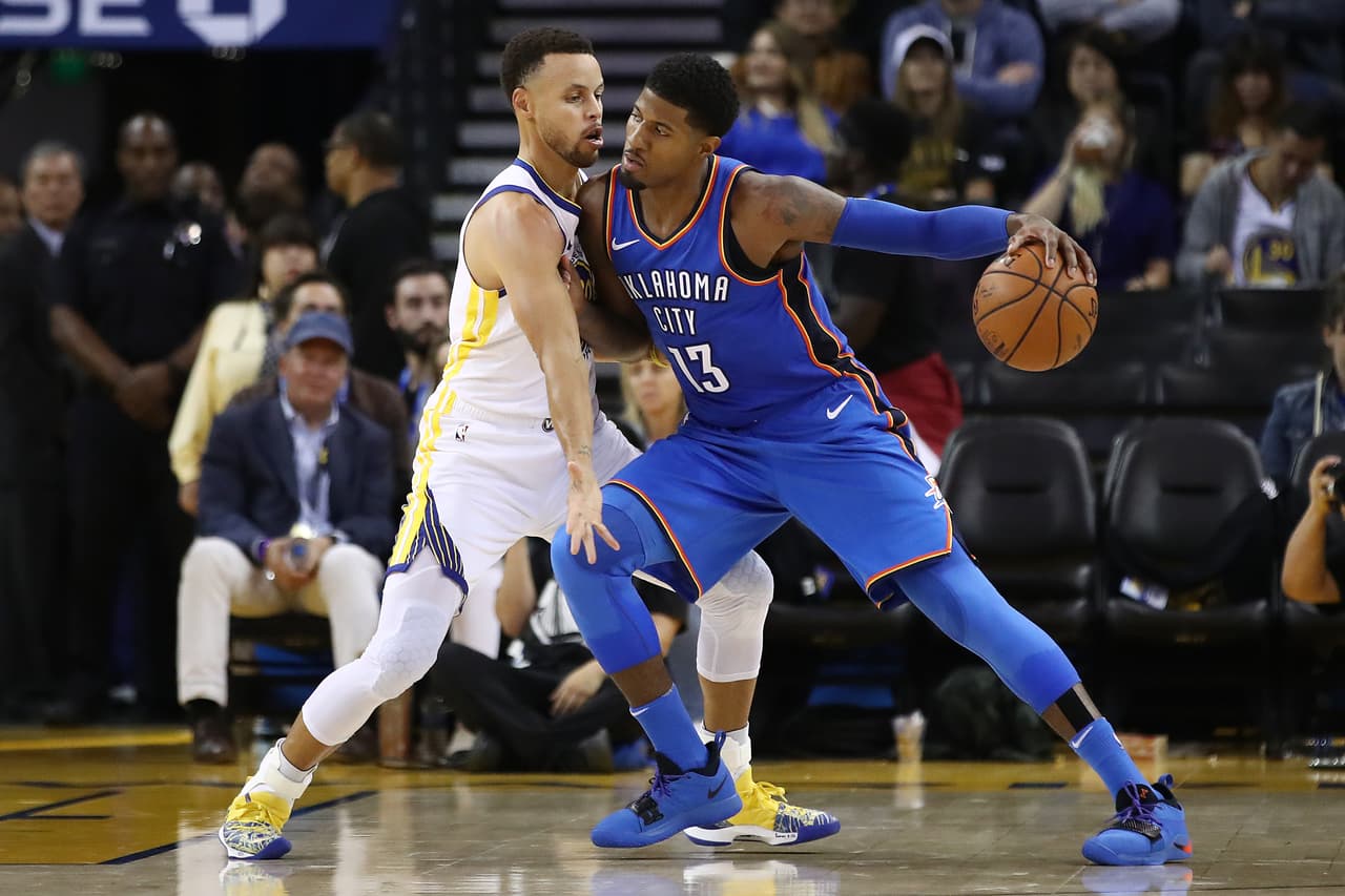 OAKLAND, CA - OCTOBER 16: Paul George #13 of the Oklahoma City Thunder drives with the ball against Stephen Curry #30 of the Golden State Warriors during their NBA game at ORACLE Arena on October 16, 2018 in Oakland, California. NOTE TO USER: User expressly acknowledges and agrees that, by downloading and or using this photograph, User is consenting to the terms and conditions of the Getty Images License Agreement. (Photo by Ezra Shaw/Getty Images)