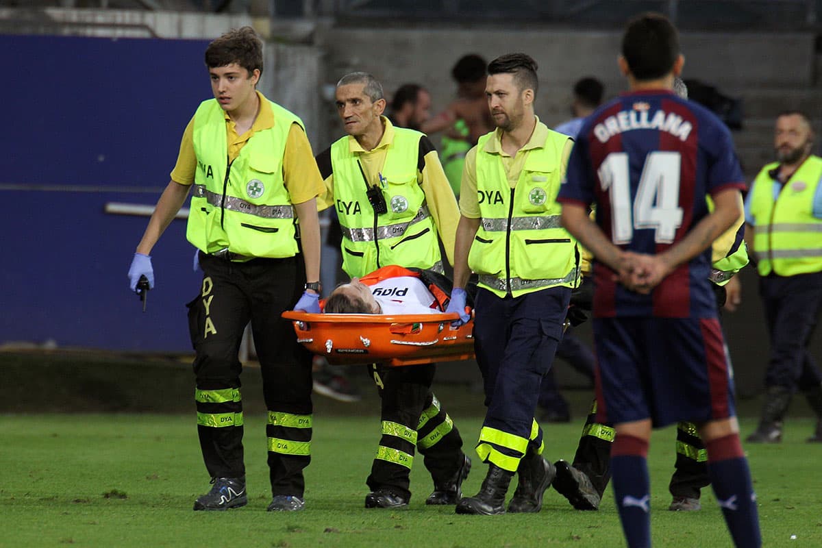 Un hombre y una mujer fueron retirados en camilla luego del accidente. El mediocampista chileno del Eibar, Fabián Orellana (derecha) observa la situación.