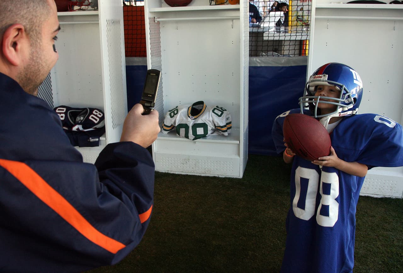 A man takes a picture of his son at the NFL Experience outside the University of Phoenix Stadium in Glendale, Arizona, 02 February 2008, on the eve of the NFL's Super Bowl XLII football game between the New England Patriots and the New York Giants. AFP PHOTO/Gabriel BOUYS (Photo credit should read GABRIEL BOUYS/AFP/Getty Images)