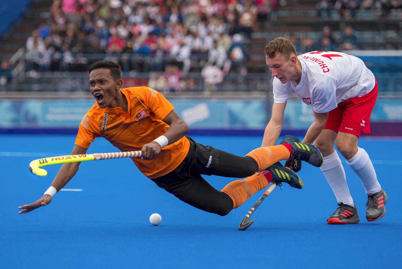 Gakub Chumenczuk de Poland (der) le provoca un trompicón a Akhimullah Anuar de Malasia en un partido de la ronda preliminar del hockey sobre césped entre Polonia y Malasia.