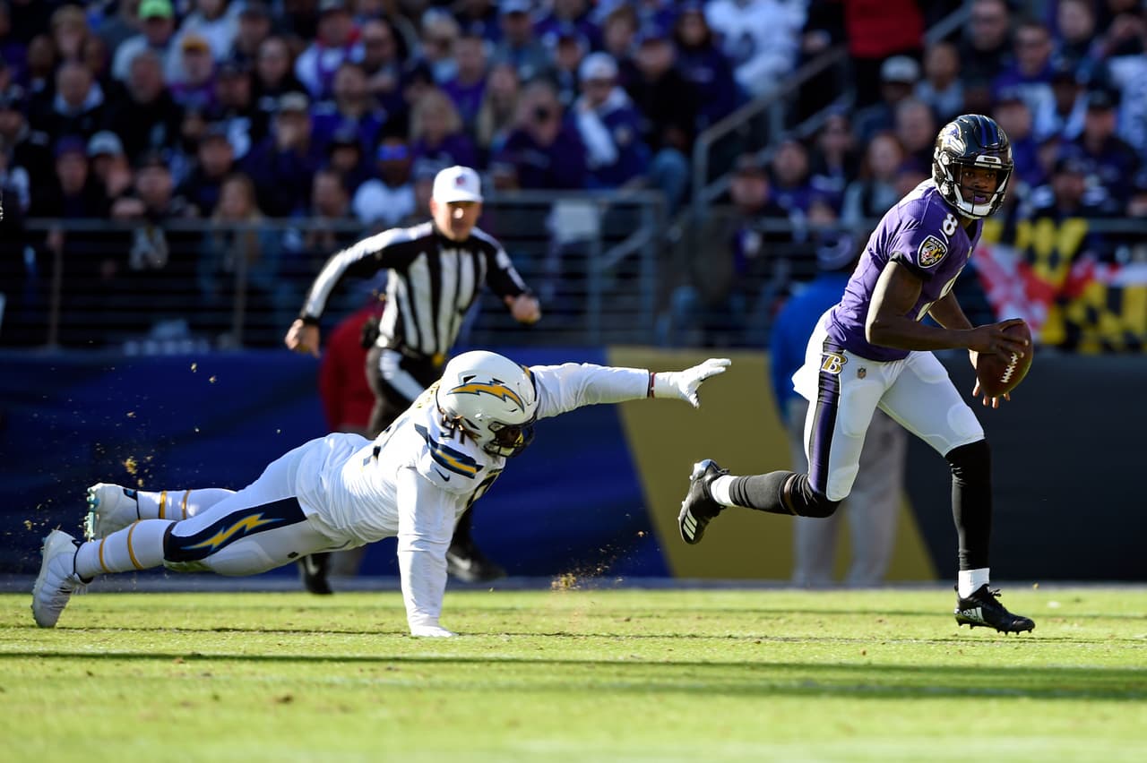 Baltimore Ravens quarterback Lamar Jackson, right, rushes past Los Angeles Chargers defensive tackle Justin Jones in the first half of an NFL wild card playoff football game, Sunday, Jan. 6, 2019, in Baltimore. (AP Photo/Gail Burton)