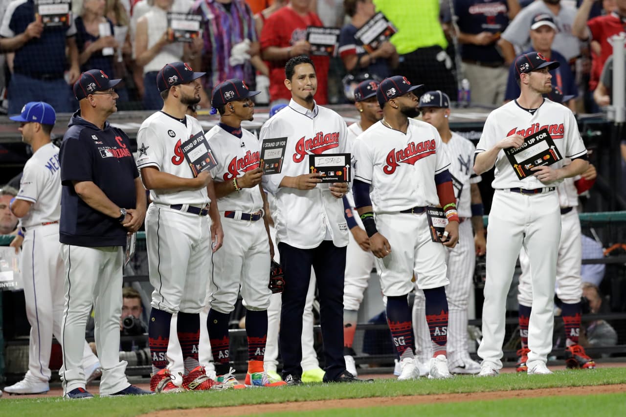Carlos Carrasco, al centro sin gorra, de los Cleveland Indians, está parado junto a sus compañeros en el quinto inning del MLB All-Star Game, en medio de la campaña "Stand Up to Cancer". Hace días le diagnosticaron leucemia.