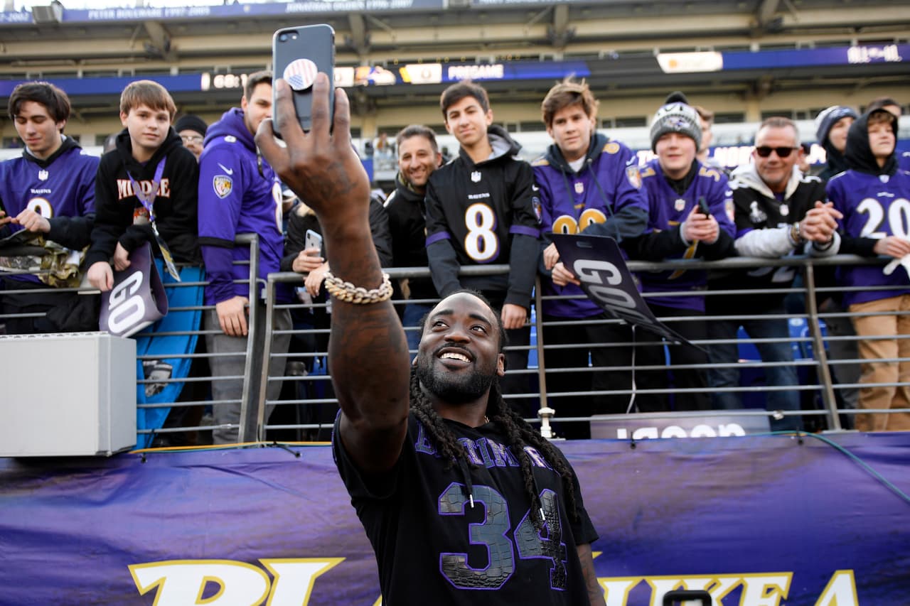 El corredor de los Baltimore Ravens Alex Collins (centro) se toma una selfie con los fanáticos de su equipo.