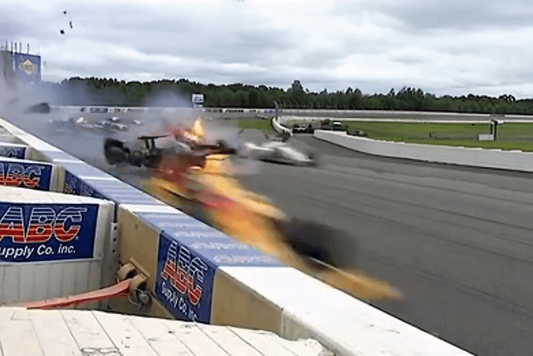 Se alcanza a ver cómo sale fuego del monoplaza de Wickens a medida que va arrastrándose el auto sin control sobre la pista del Pocono Raceway.