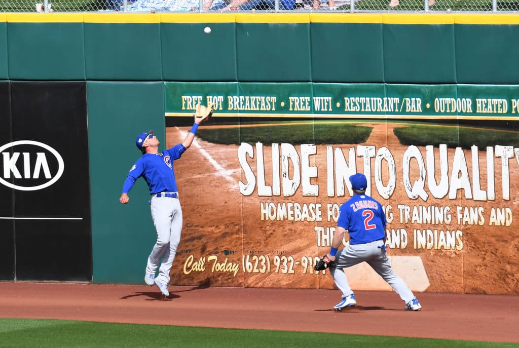 Albert Almora J. de los Chicago Cubs hace una atrapada en la franja de advertencia en partido de pretemporada en Arizona contra los Cincinnati Reds.