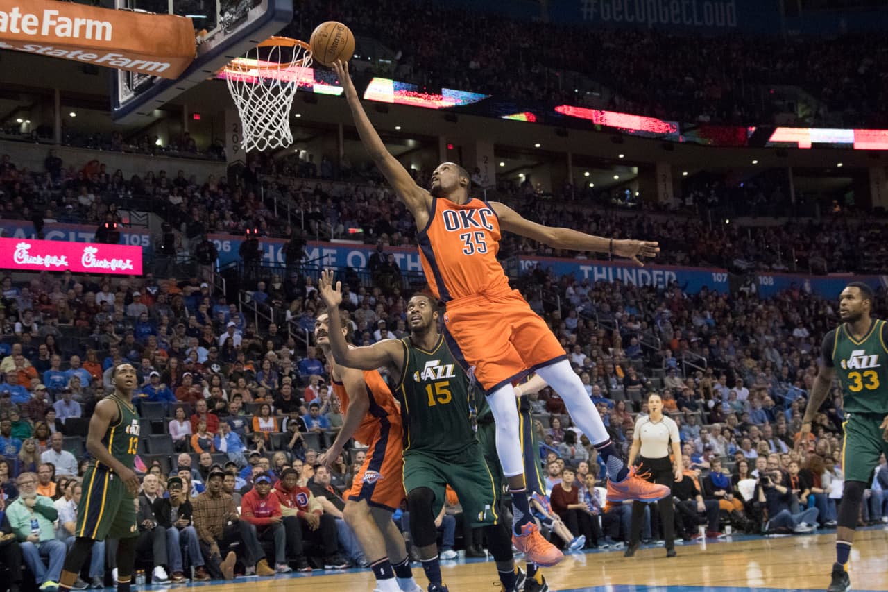 OKLAHOMA CITY, OK - DECEMBER 13 : Kevin Durant #35 of the Oklahoma City Thunder sails past Derrick Favors #15 of the Utah Jazz for two points during the third period of a NBA game at the Chesapeake Energy Arena on December 13, 2015 in Oklahoma City, Oklahoma. The Thunder won 104-98 in overtime.NOTE TO USER: User expressly acknowledges and agrees that, by downloading and or using this photograph, User is consenting to the terms and conditions of the Getty Images License Agreement. (Photo by J Pat Carter/Getty Images)