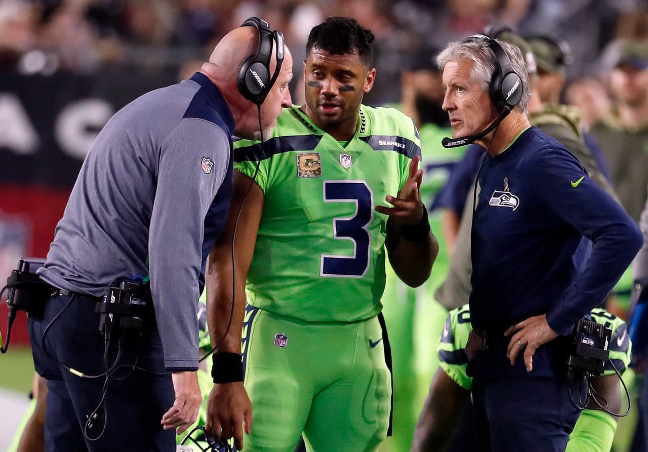 ARCHIVO - En esta foto del 9 de noviembre de 2017, el quarterback de los Seahawks, Russell Wilson (3), habla con el entrenador Pete Carroll, derecha, y el asistente Tom Cable en un partido contra los Cardinals en Glendale, Arizona. (AP Foto/Rick Scuteri, Archivo)