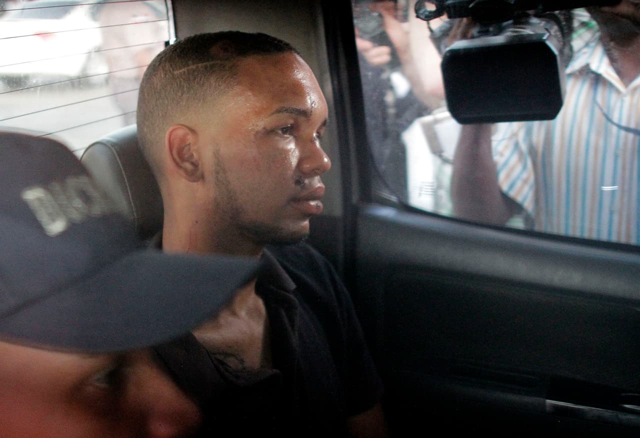 El motociclista Eddy Vladimir Féliz García (foto), arrestado en 2017 por posesión de drogas, figuraba entre varias personas detenidas el martes por la tarde. Un auto policial que transportaba a Féliz García llegó a un contenedor naviero improvisado como tribunal el martes por la noche. El detenido se sentó ahí durante aproximadamente media hora, antes de marcharse de nuevo. Funcionarios judiciales dijeron que la audiencia se había demorado porque los documentos de cargo contra Féliz García no habían llegado a tiempo. Sin embargo, añadieron que esperaban que el sospechoso volviera después.