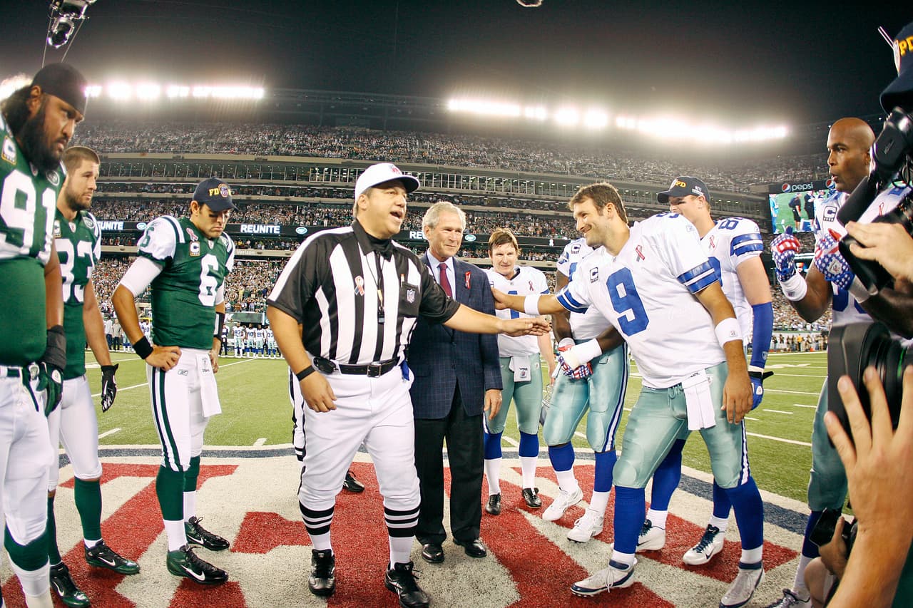 Dallas Cowboys quarterback Tony Romo (9) pats former U.S. President George W. Bush on the arm after the Cowboys won the coin toss as NFL referee Alberto Riveron (center) announces the result before an NFL football game against the New York Jets Sunday, September 11, 2011 at MetLife Stadium in East Rutherford, New Jersey. The Jets won the game, 27-24. (AP Photo/James D Smith)