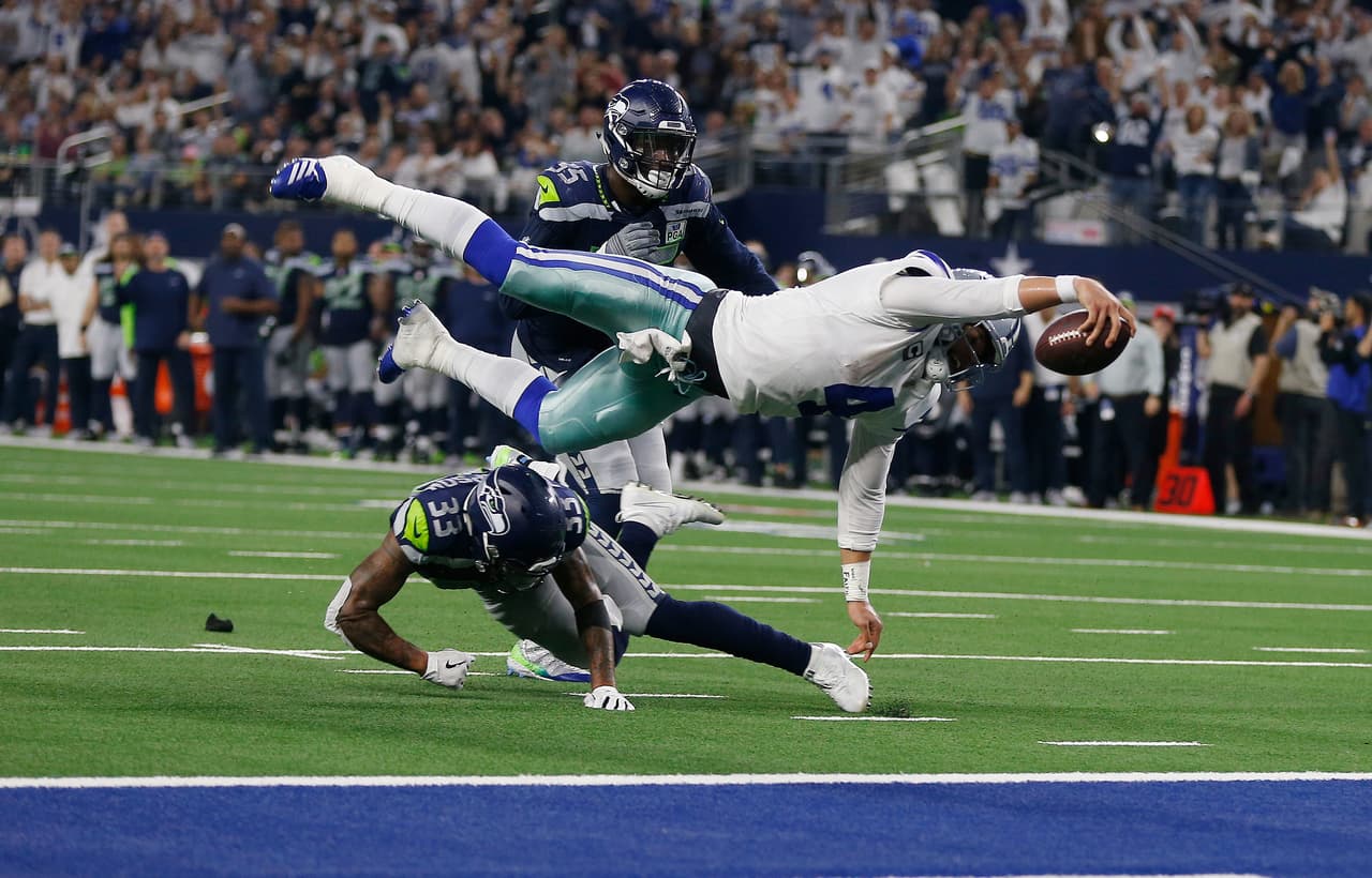 Dallas Cowboys quarterback Dak Prescott (4) flies for the goal line and makes a first down against Seattle Seahawks defensive end Frank Clark (55) during the second half of the NFC wild-card NFL football game in Arlington, Texas, Saturday, Jan. 5, 2019. (AP Photo/Ron Jenkins)