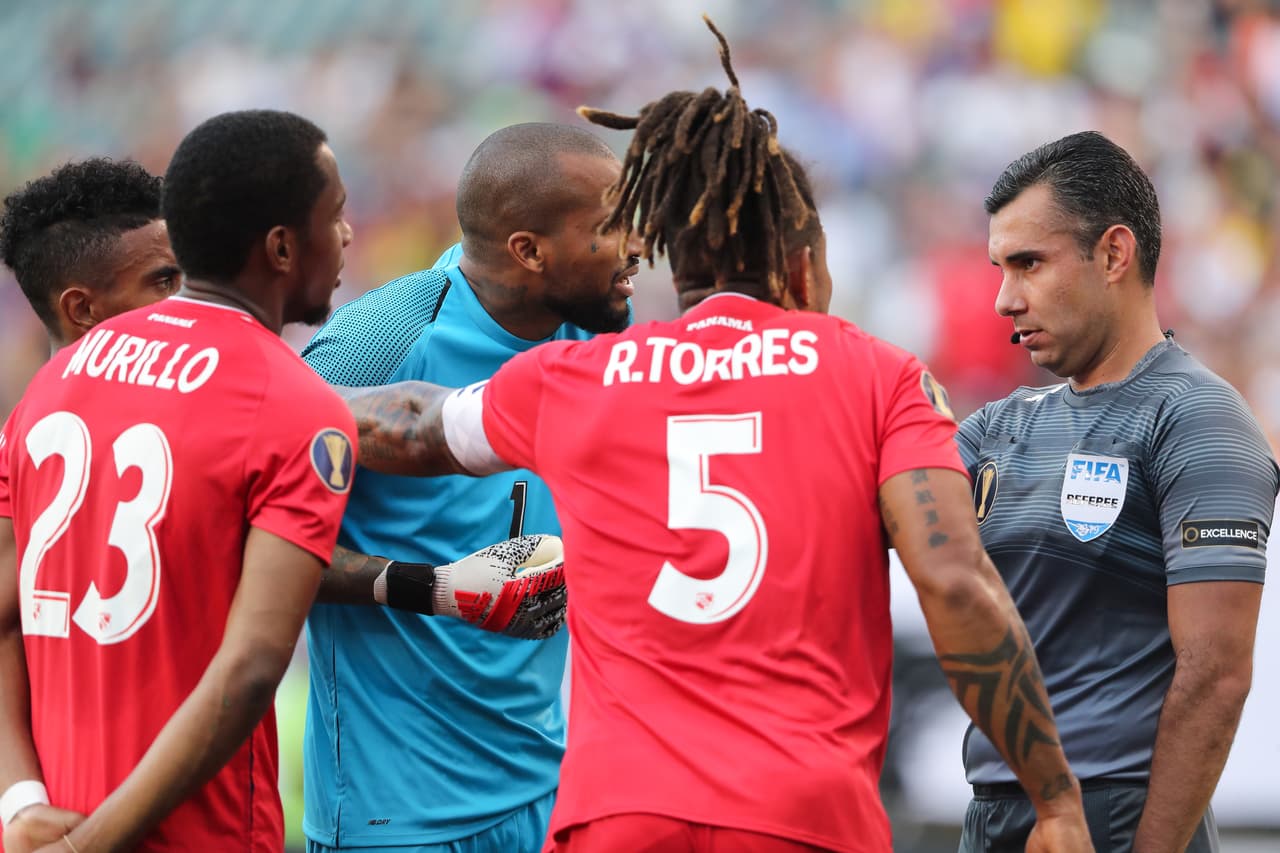 El árbitro Mario Escobar de Guatemala (derecha) decretó penalti a favor de Jamaica al minuto 74' tras la mano de Michael Murillo (izquierda).
