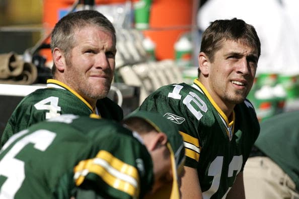 GREEN BAY, WI - OCTOBER 9: Quarterback Brett Favre #4 and quarterback Aaron Rodgers #12 of the Green Bay Packers look on from the sideline during a game against the New Orleans Saints at Lambeau Field on October 9, 2005 in Green Bay, Wisconsin. The Packers defeated the Saints 52-3. (Photo by Joe Robbins/Getty Images)