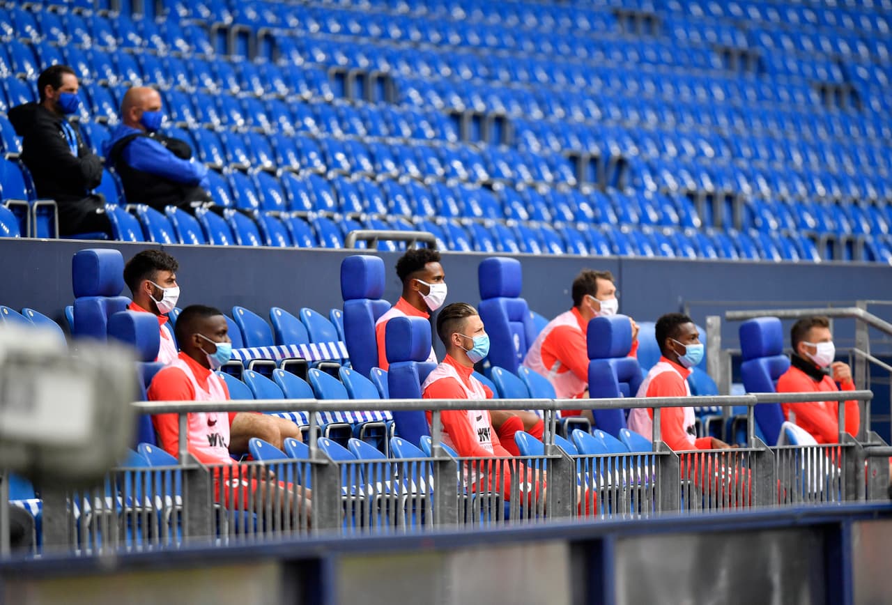 Los jugadores guardan la distancia social en la banca, ahora en la tribuna, mientras esperan su turno para ingresar al terreno de juego. Así es el regreso del futbol alemán.