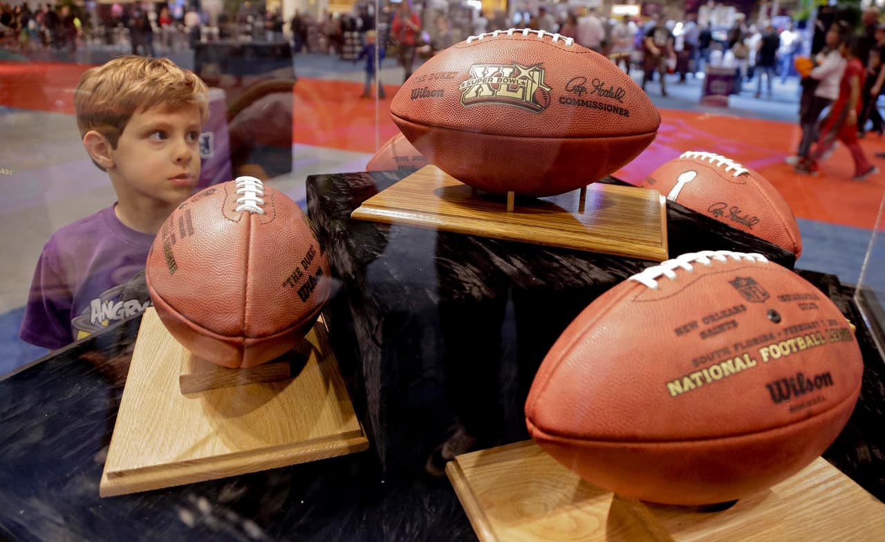 A young NFL football fan looks through a display case containing past Super Bowl game balls at the NFL Experience, Friday, Feb. 1, 2013, in New Orleans. The Baltimore Ravens play the San Francisco 49ers in Super Bowl XLVII on Sunday. (AP Photo/Julie Jacobson)