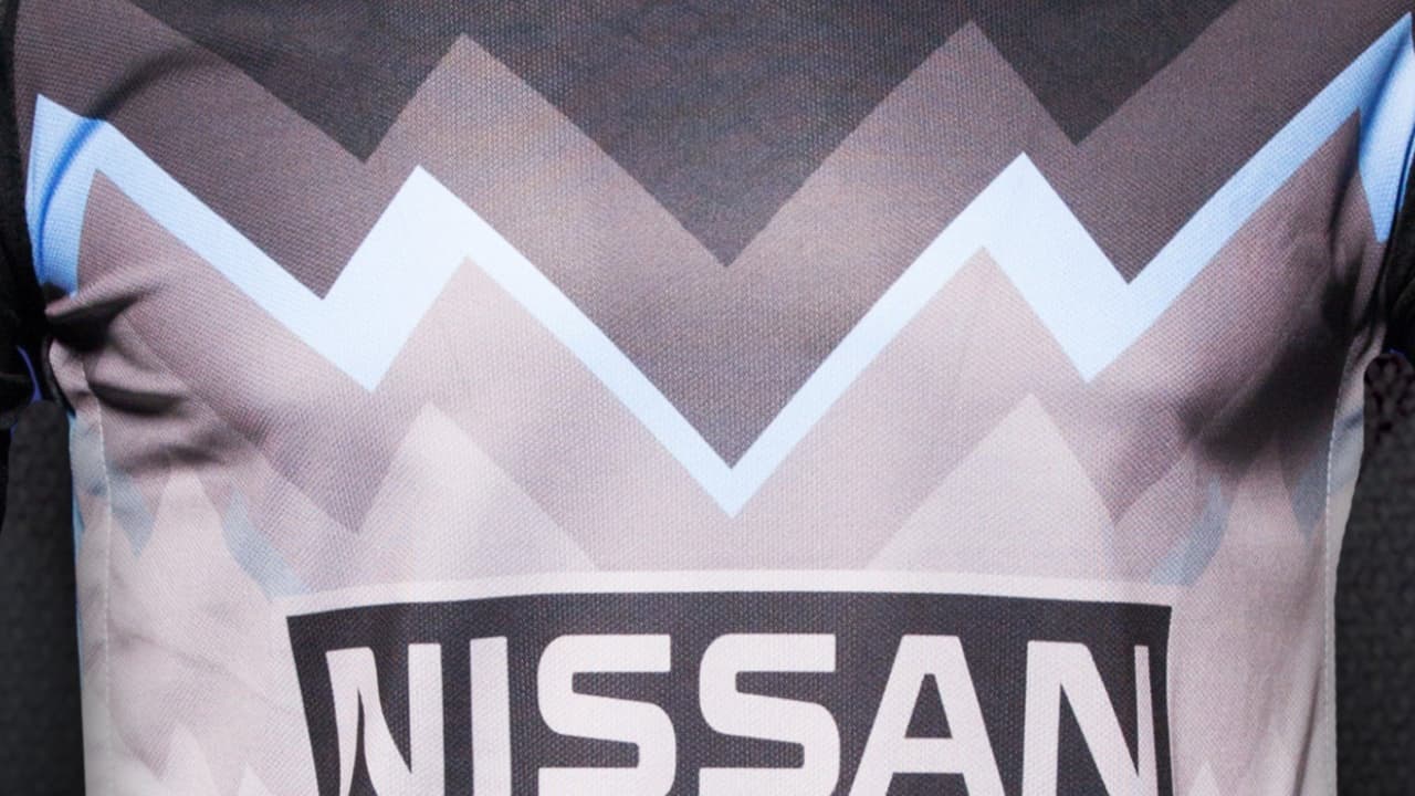 Los tonos grises y negros, junto a una franja azul, son protagonistas de este jersey.