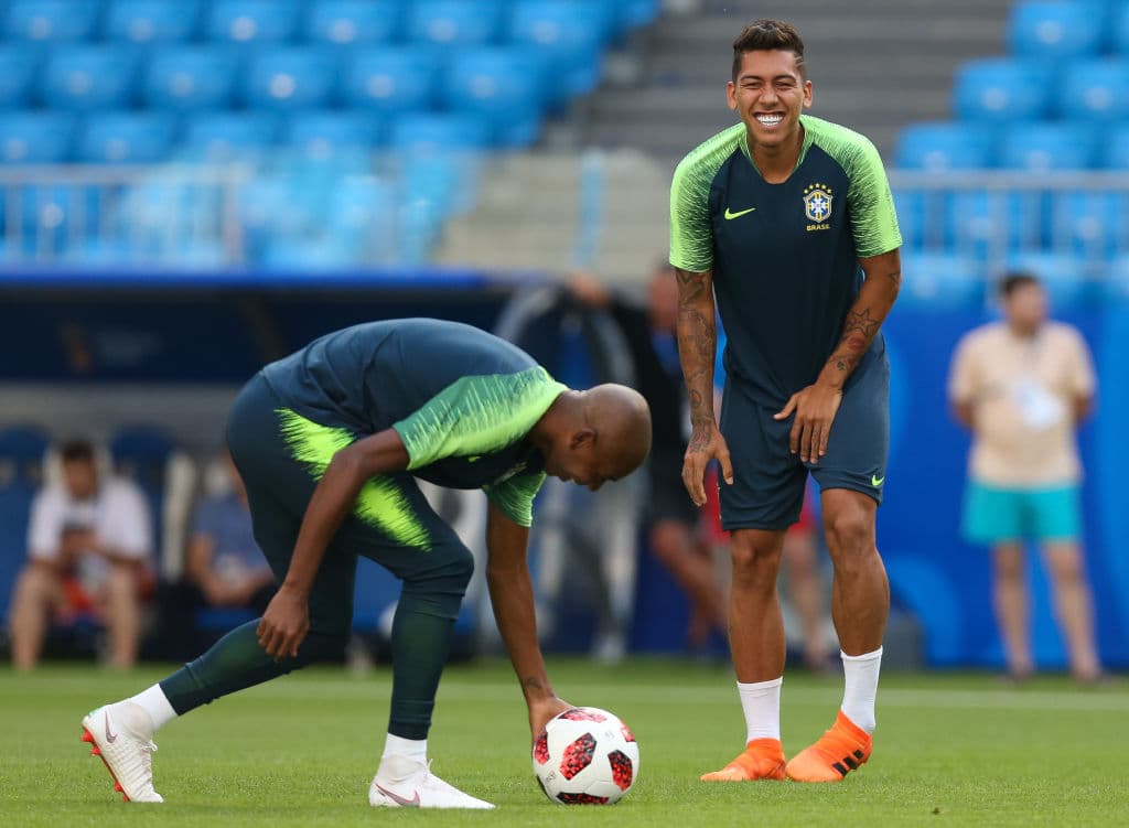 Roberto Firmino ríe mientras Fernandinho se agacha a acomodar el balón en una gráfica que indica el buen ambiente dentro del equipo brasileño para tan importante compromiso.