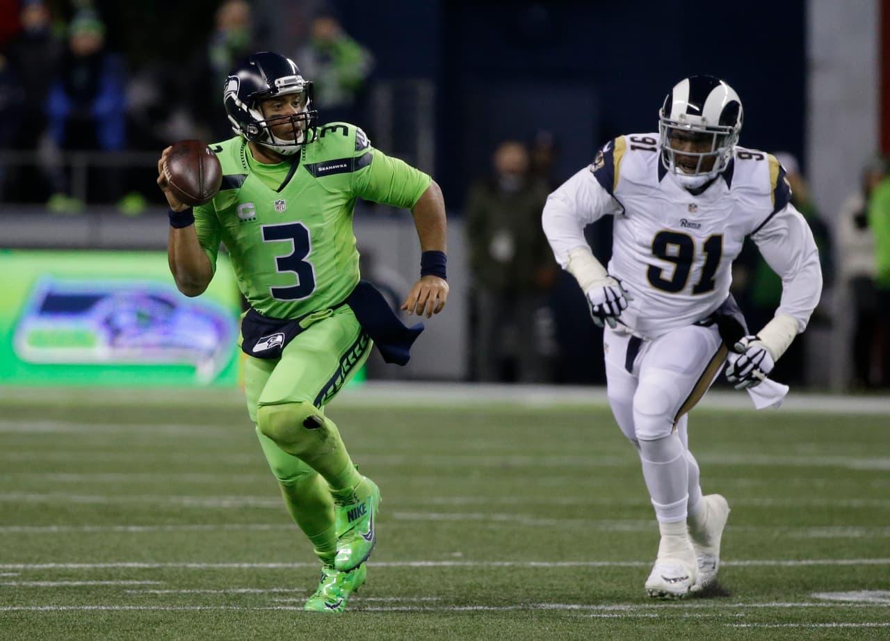 Seattle Seahawks quarterback Russell Wilson scrambles as Los Angeles Rams defensive tackle Dominique Easley (91) pursues in the first half of an NFL football game, Thursday, Dec. 15, 2016, in Seattle. (AP Photo/Elaine Thompson)