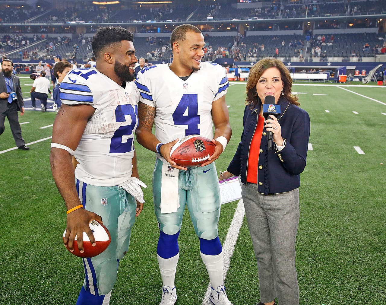 Dallas Cowboys running back Ezekiel Elliott (21) and quarterback Dak Prescott (4) talk with NBC Sports reporter Michele Tafoya (right) after the 2016 NFL week 3 regular season game against the Chicago Bears, Sunday, Sept. 25, 2016, in Arlington, Texas. The Cowboys defeated the Bears, 31-17. (James D. Smith via AP)