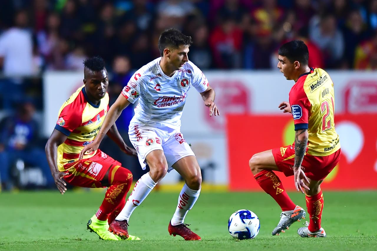 Mauro Lainez driblea y deja atrás a los jugadores de Morelia José Ortiz y Quick Mendoza.