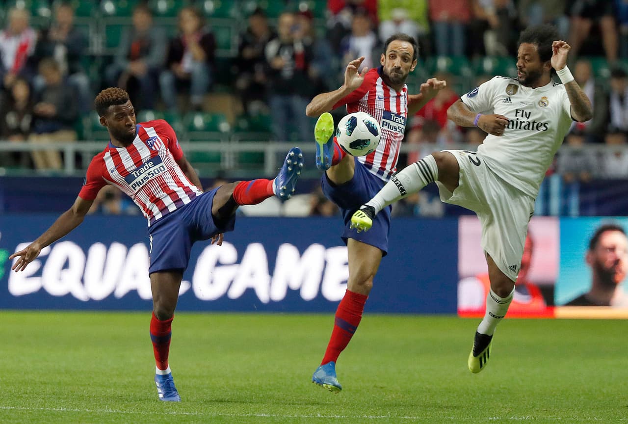Atletico's Thomas Lemar, left, Atletico's Juanfran, center, and Real Madrid's Marcelo challenge for the ball during the UEFA Super Cup final soccer match between Real Madrid and Atletico Madrid at the Lillekula stadium in Tallinn, Estonia, Wednesday, Aug. 15, 2018. (AP Photo/Mindaugas Kulbis)