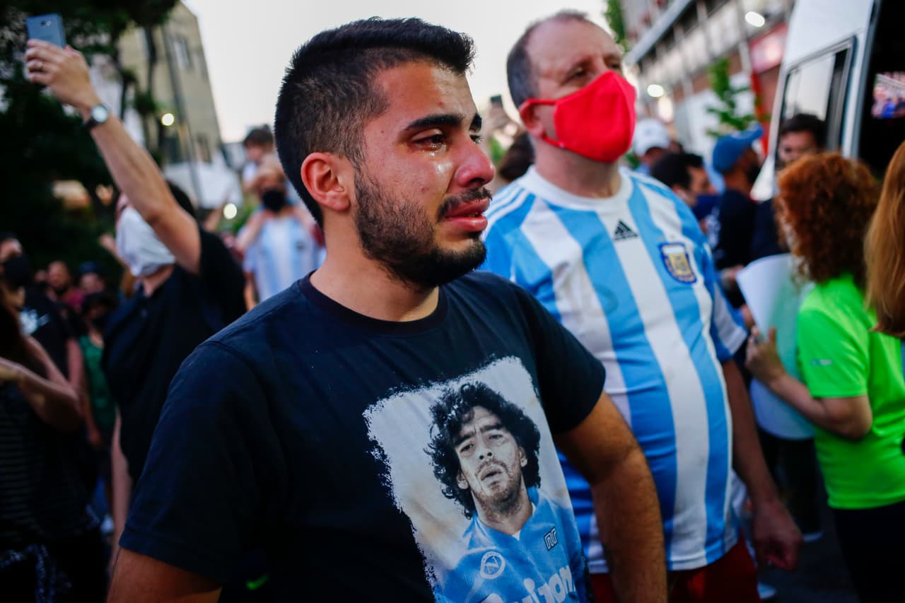 Un hombre llora con una camiseta con la imagen de Maradona en sus tiempos en el Napoli, club italiano en el que también forjó su leyenda. El pequeño equipo del sur de Italia cambió su historia de la mano del astro argentino.