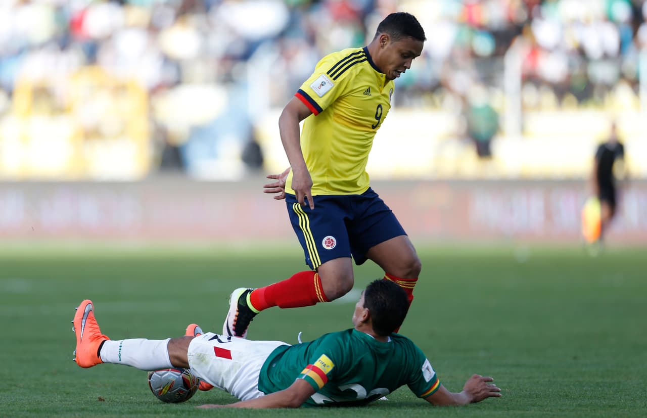 El jugador de Bolivia, Edward Zenteno, en el suelo, intenta detener al jugador de Colombia Luis Muriel en un partido por las eliminatorias mundiaslitas el jueves, 24 de marzo de 2016, en La Paz. (AP Photo/Juan Karita)