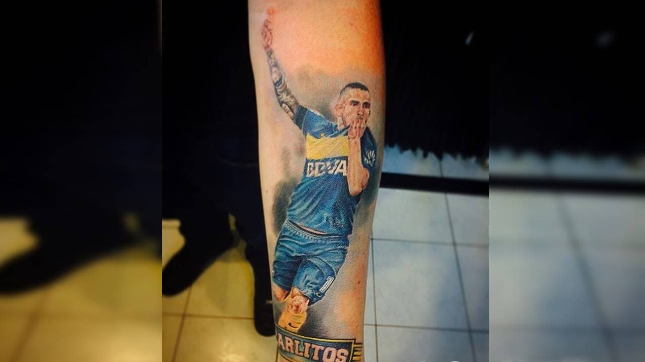 Carlitos Tévez besa el escudo del club de sus amores en el brazo de un aficionado.