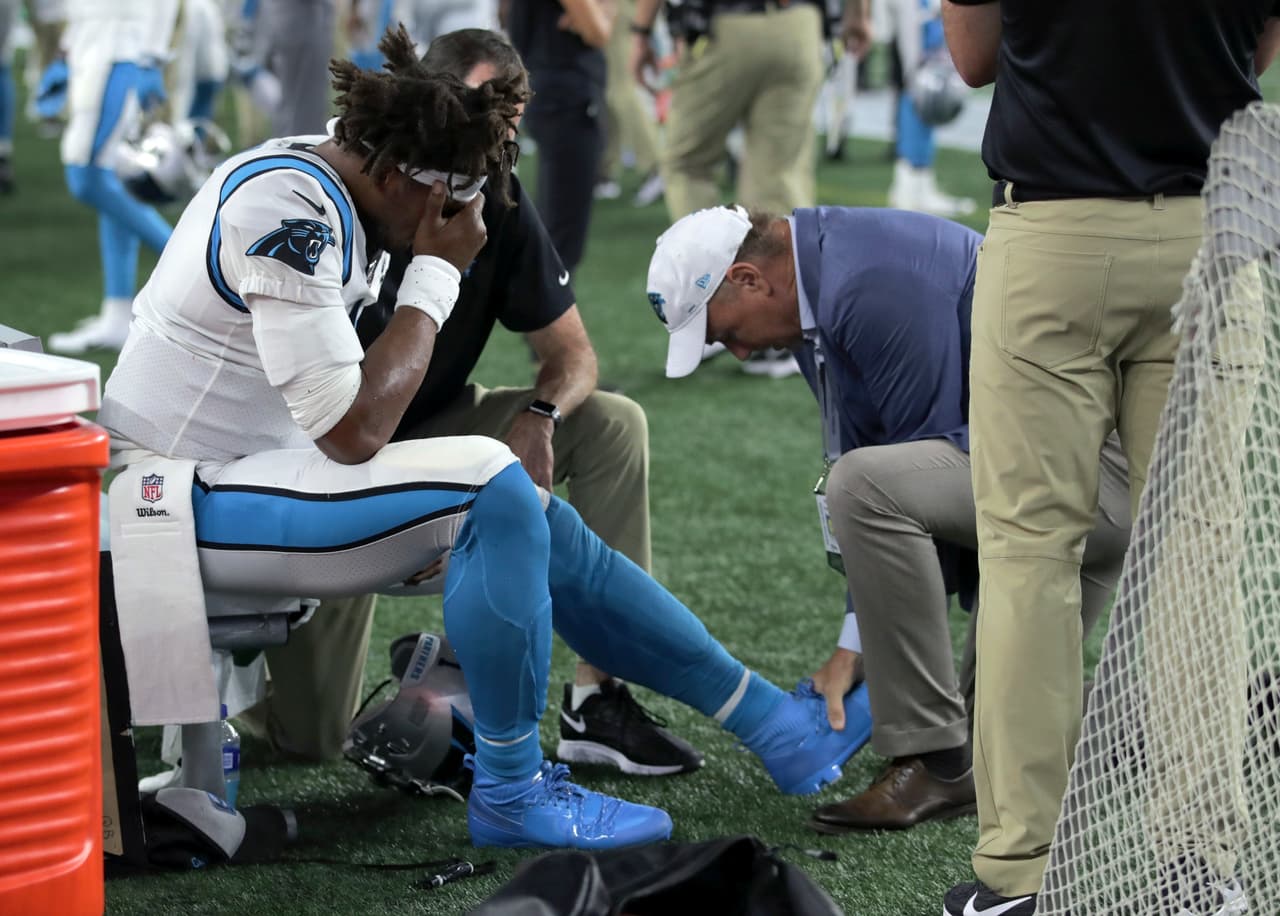 El cuarter backe de Carolina Panthers, Cam Newton (1) recibe atención en las líneas laterales tras una lesión en la primera mitad del partido ante New England Patriots.