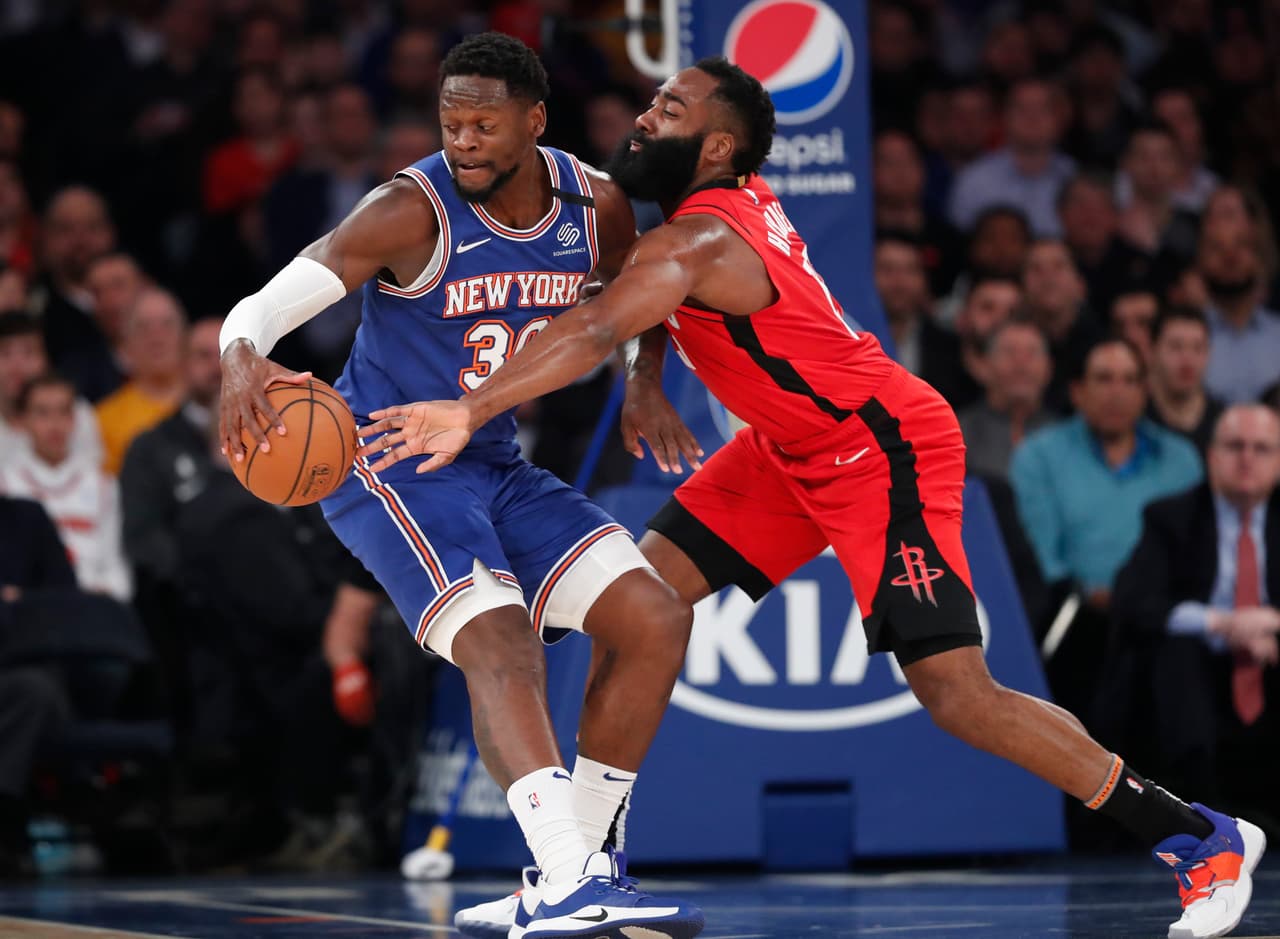 James Hardenle roba el balón a Julius Randle quien intenta esconder el balón pero fracasa ante el guardia de los Houston Rockets.