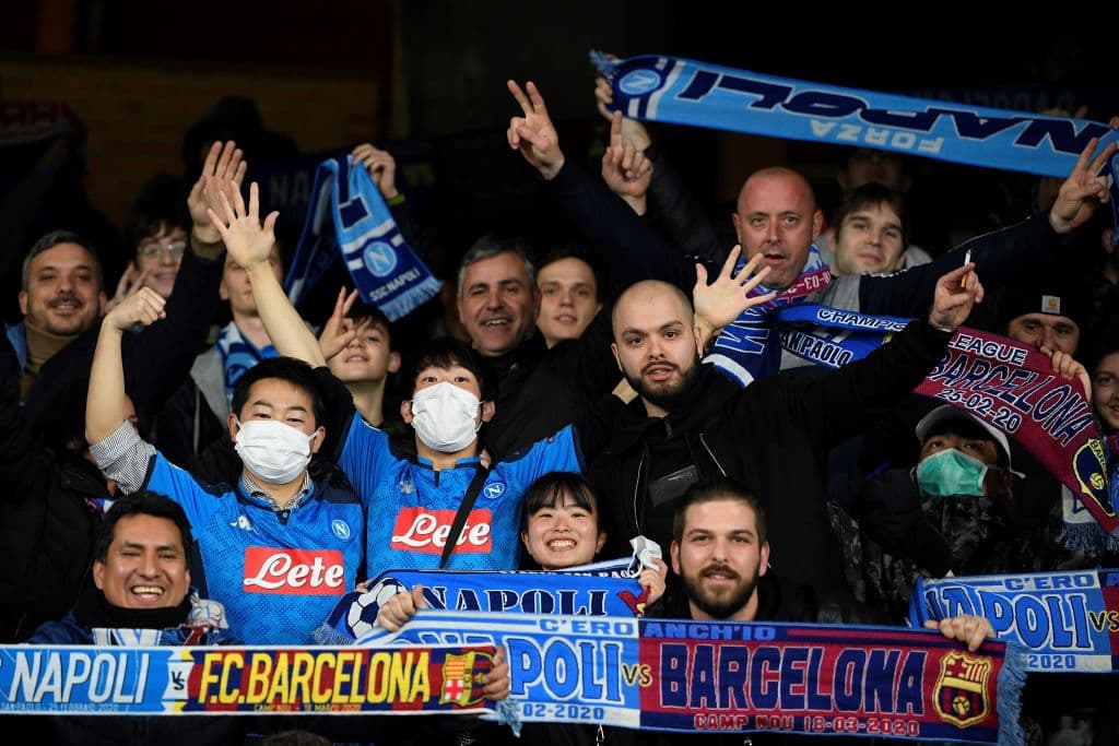 Aficionados con rasgos asiáticos entre los napolitanos, sin quitarse el cubrebocas.