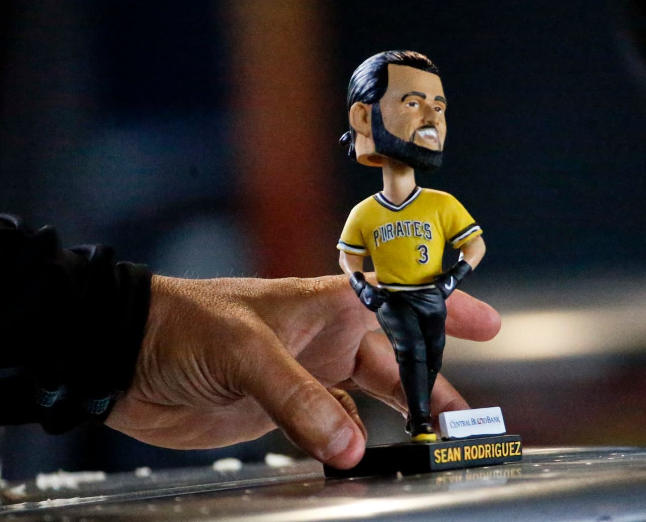 A man moves a bobble head of Pittsburgh Pirates' Sean Rodriguez that was given away at PNC Park to patrons at a baseball game between the Pittsburgh Pirates and the Arizona Diamondbacks, Saturday, June 23, 2018, in Pittsburgh. (AP Photo/Keith Srakocic)