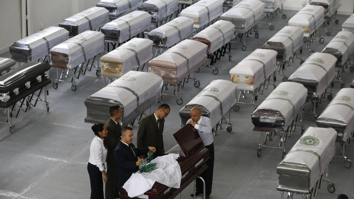Empleados de una funeraria cubren un féretro, decorado con un escudo del club de fútbol Chapecoense, con los restos mortales de un miembro del equipo, en Medellín, Colombia, el 2 de diciembre de 2016. Fernando Vergara/AP
