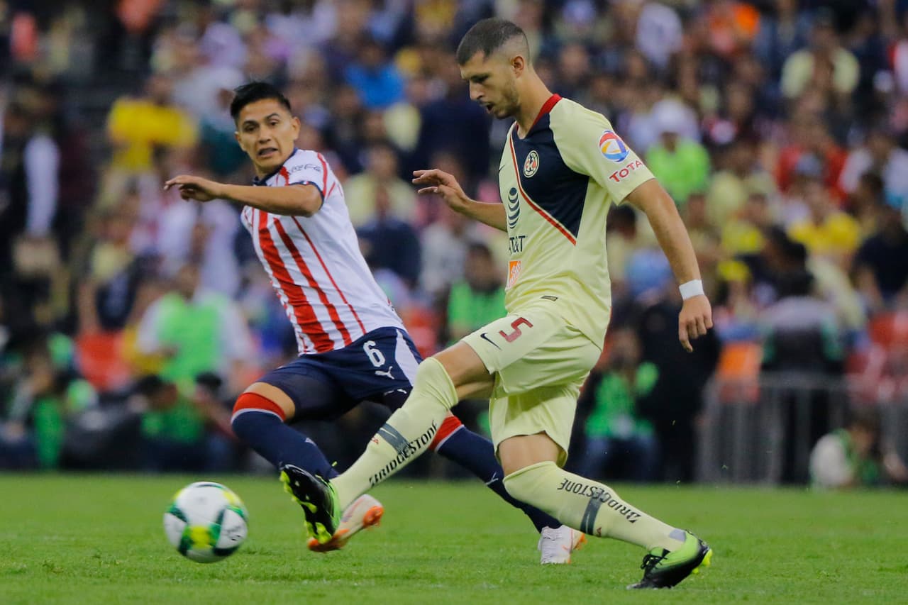 Por América Guido Rodríguez y Dieter Villalpando (6) de las Chivas en acciones de una muy intensa primera mitad. El jugador de las Águilas buscando filtrar un balón al área Rojiblanca.
