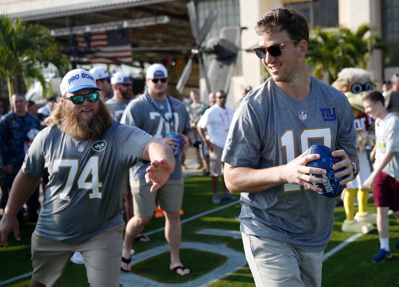 Eli Manning vacilando con el centro de los New York Jets, Nick Mangold, durante el draft del Pro Bowl en el Army Airfield.