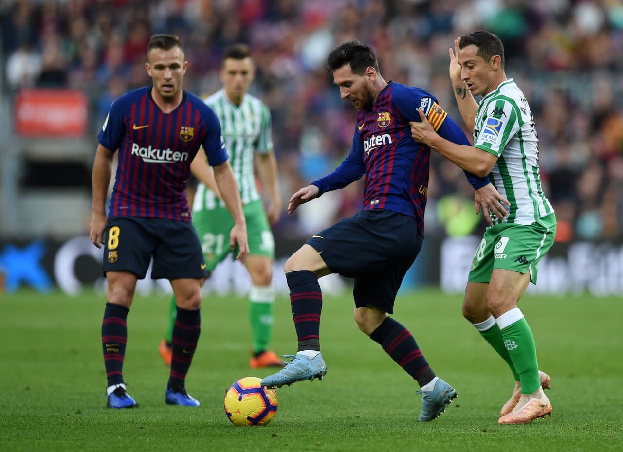 BARCELONA, SPAIN - NOVEMBER 11: Lionel Messi of Barcelona is challenged by Andres Guardado of Real Betis during the La Liga match between FC Barcelona and Real Betis Balompie at Camp Nou on November 11, 2018 in Barcelona, Spain. (Photo by Alex Caparros/Getty Images)
