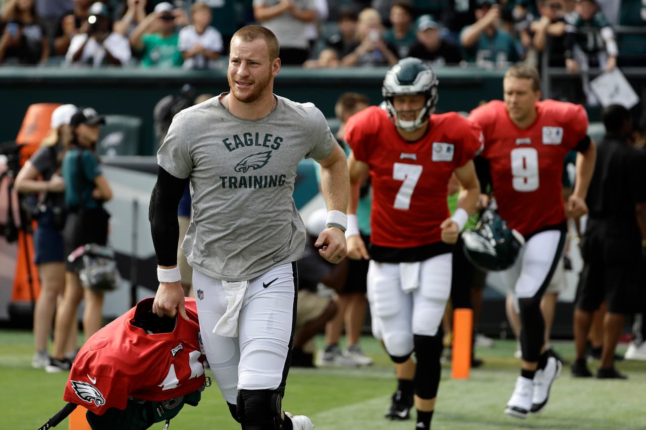 Carson Wentz entra al campo de entrenamiento de los Eagles seguido por Nate Sudfeld y Nick Foles.
