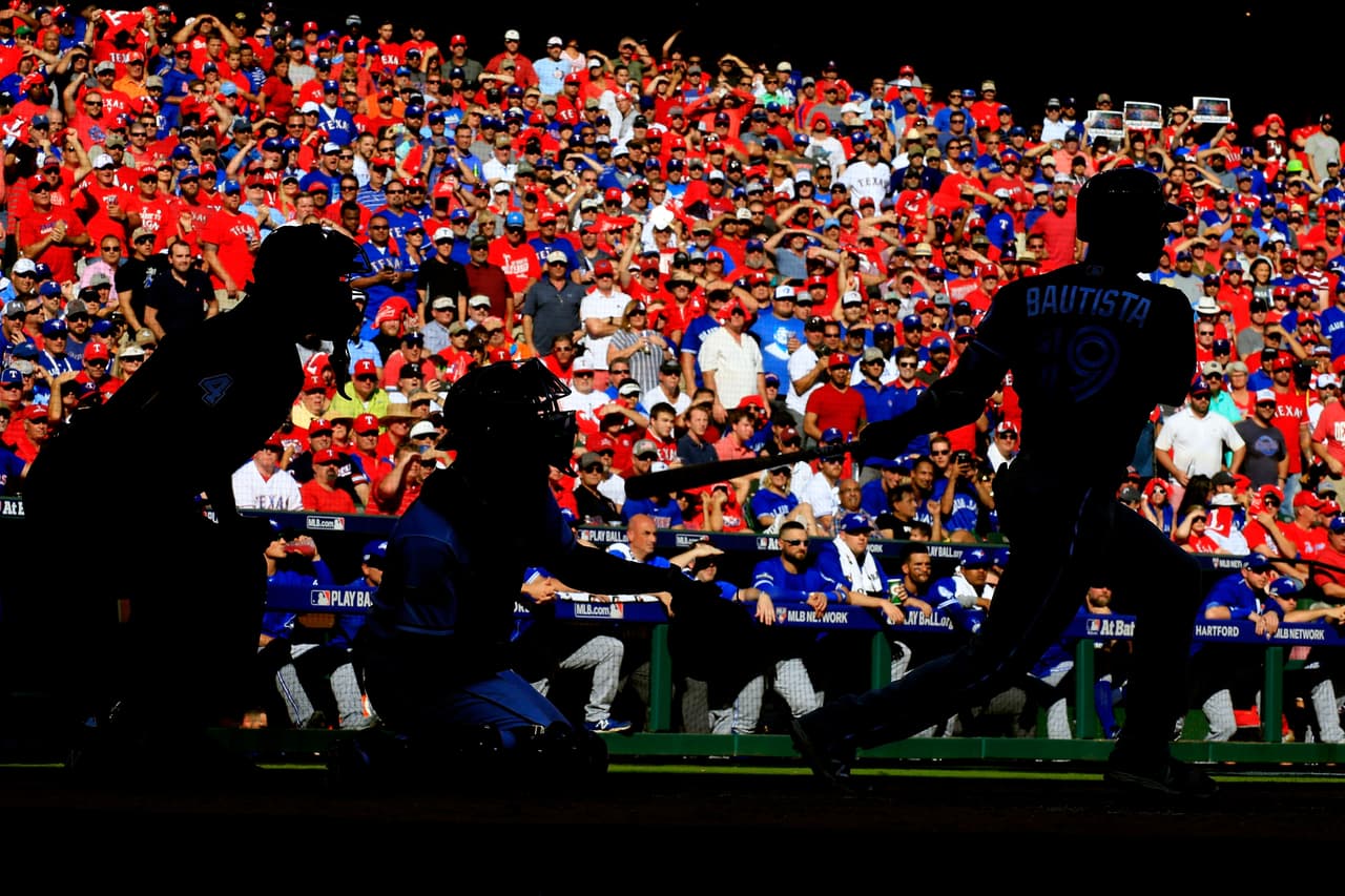 En sombras, el batazo de José Bautista de Toronto Blue Jays contra los Rangers de Texas durante la tercera entrada en el primer juego de la División de la serie de la Liga Americana.