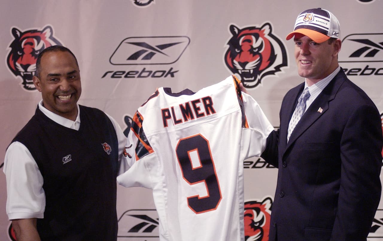 2003 CARSON PALMER | QB Southern Cal - 
<b>Cincinnati Bengals</b>
<br>
<br>El mariscal de campo Carson Palmer y el entrenador de Cincinnati, Marvin Lewis, sostienen un jersey de los Bengals durante una conferencia de prensa en el Estadio Paul Brown en Cincinnati, el jueves 24 de abril de 2003. Palmer, elegido #1 global por los Bengals en el NFL Draft, firmó un contrato con el equipo.