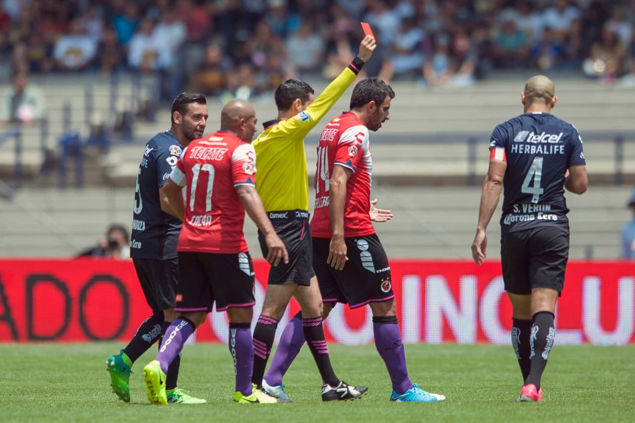 César Arturo Ramos tuvo un día complicado, mostró dos tarjetas rojas, ambas a jugadores de Pumas. Aquí vemos a Darío Verón siendo expulsado.