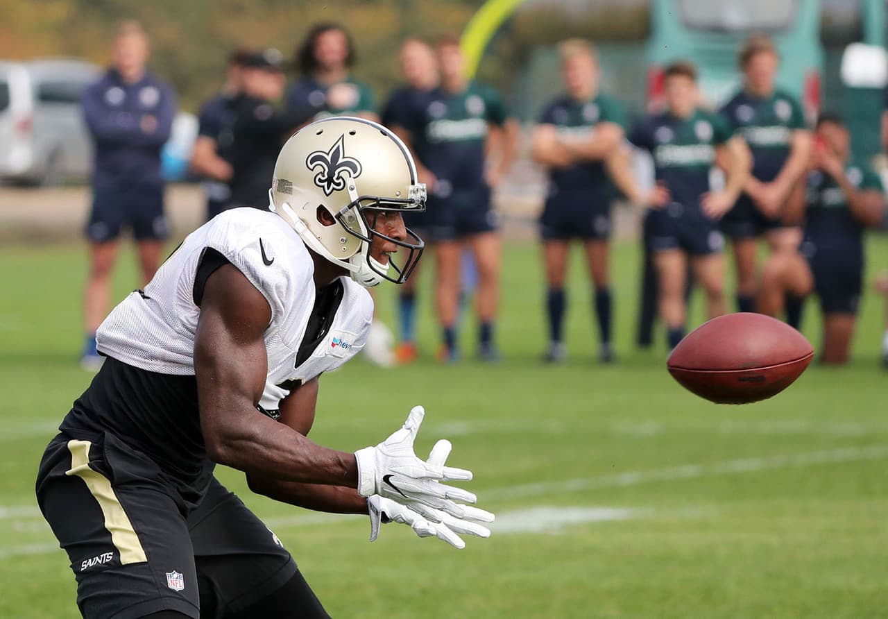 El receptor estrella de los Saints, Michael Thomas, atrapa el balón mientras está siendo observado por el equipo de London Irish Rugby durante la práctica en Londres.